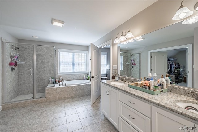 bathroom with a garden tub, a sink, a spacious closet, a shower stall, and double vanity