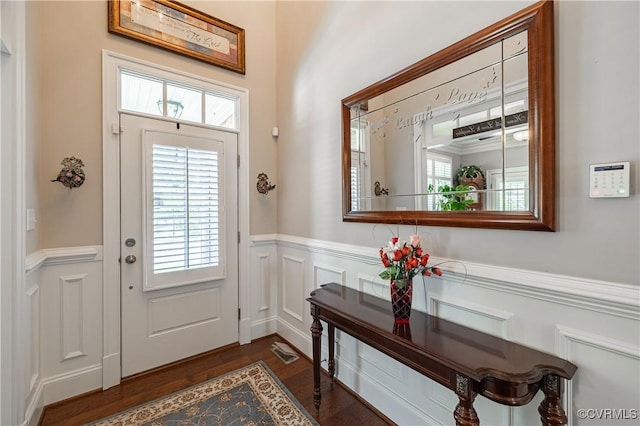 foyer with a wainscoted wall, visible vents, a decorative wall, and dark wood-style flooring