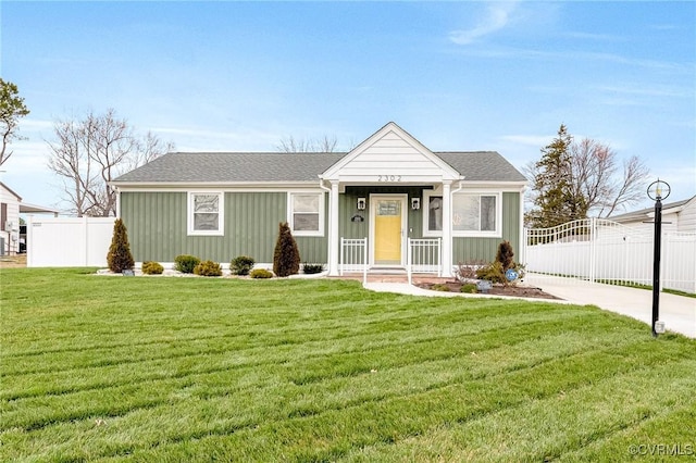 view of front of property featuring a front yard, fence, board and batten siding, and a shingled roof