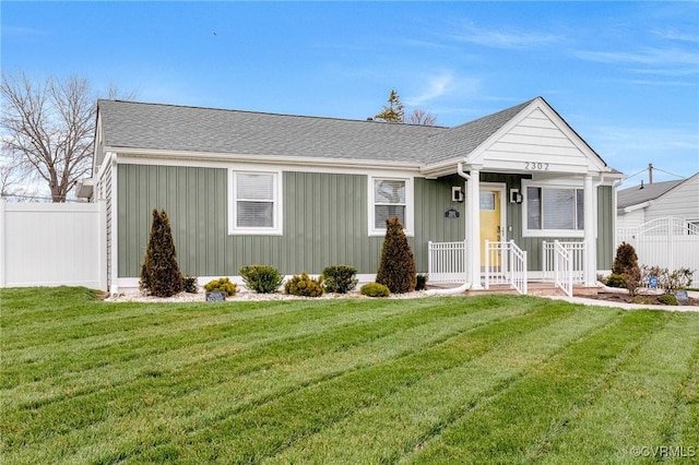 view of front facade featuring roof with shingles, a front yard, and fence