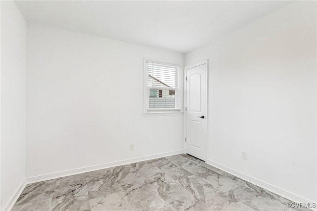 empty room featuring marble finish floor and baseboards