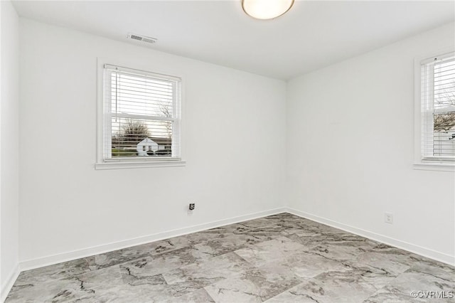 empty room featuring visible vents, baseboards, and marble finish floor