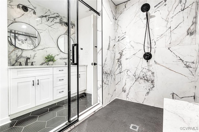 full bath featuring double vanity, a marble finish shower, a sink, and tile patterned flooring