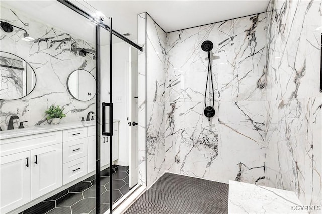 full bathroom featuring a marble finish shower, a sink, tile patterned floors, and double vanity