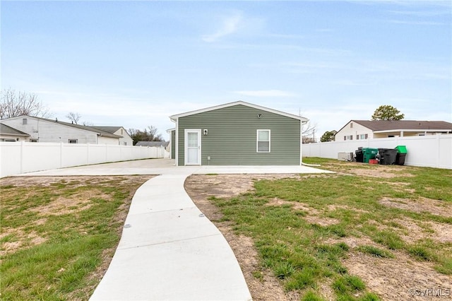 rear view of property featuring a patio, a yard, and a fenced backyard