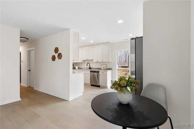 kitchen featuring white cabinets, appliances with stainless steel finishes, light countertops, a sink, and recessed lighting