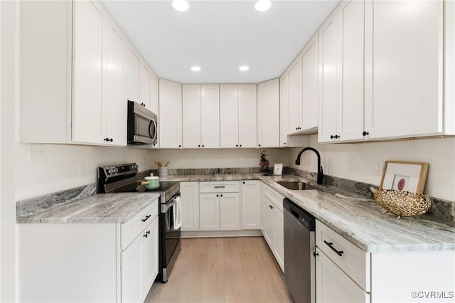 kitchen with recessed lighting, a sink, white cabinetry, appliances with stainless steel finishes, and light wood-type flooring