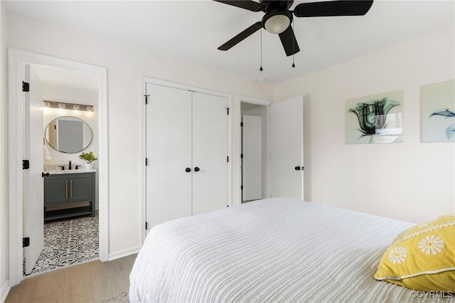 bedroom with light wood finished floors, a closet, a ceiling fan, ensuite bath, and a sink