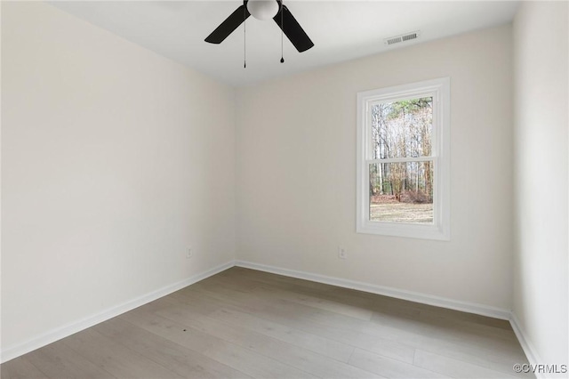 empty room featuring light wood-type flooring, baseboards, visible vents, and ceiling fan