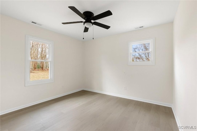 spare room featuring baseboards, ceiling fan, visible vents, and light wood finished floors