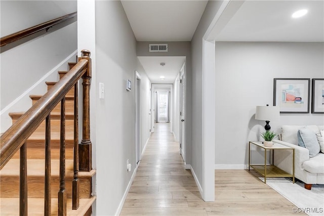 corridor with light wood-style floors, visible vents, baseboards, and stairs