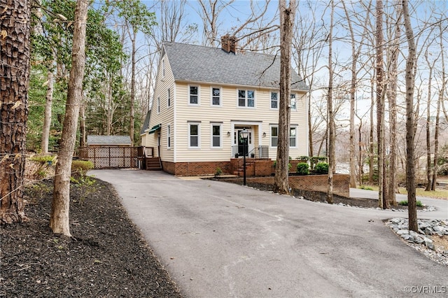 colonial-style house with a chimney and roof with shingles