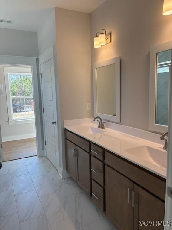 full bathroom featuring double vanity, marble finish floor, visible vents, and a sink