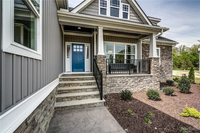 entrance to property with stone siding, a porch, and board and batten siding