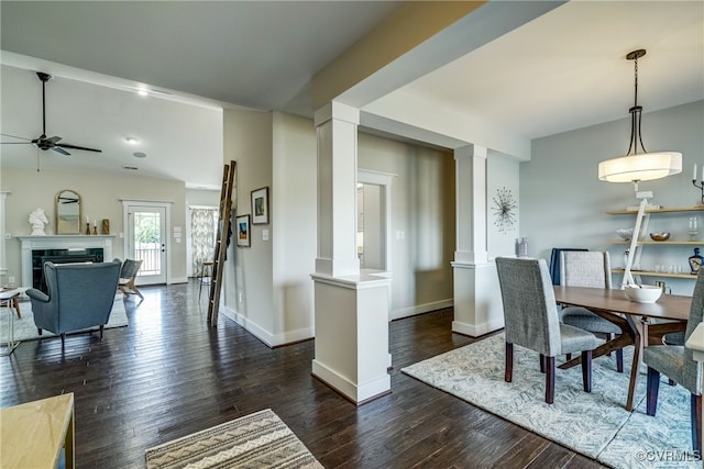 dining area with dark wood finished floors, a fireplace, decorative columns, and baseboards