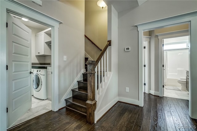 stairway featuring baseboards, washer / clothes dryer, and hardwood / wood-style floors