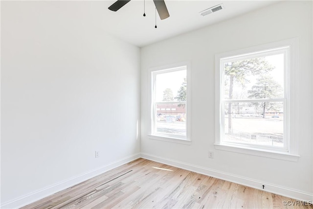 spare room featuring light wood-style floors, baseboards, visible vents, and ceiling fan