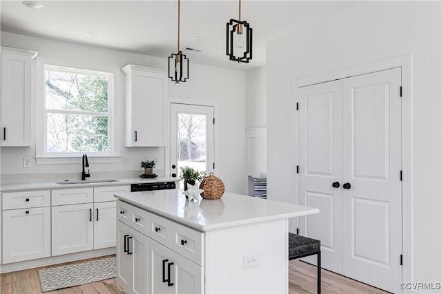 kitchen with light countertops, a sink, light wood-style flooring, and a kitchen bar