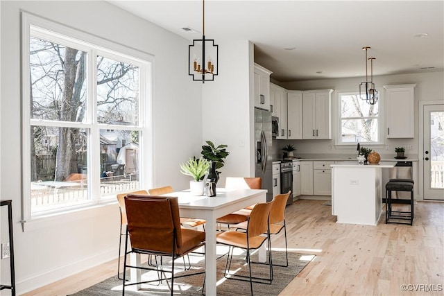 dining area featuring baseboards, light wood-type flooring, and an inviting chandelier