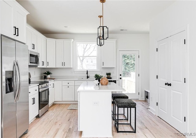 kitchen with appliances with stainless steel finishes, white cabinetry, a sink, and a breakfast bar area