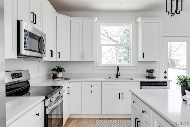 kitchen featuring white cabinetry, appliances with stainless steel finishes, light countertops, and a sink