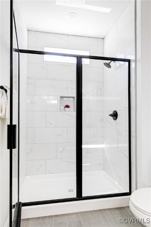 bathroom with a stall shower, toilet, and tile patterned floors