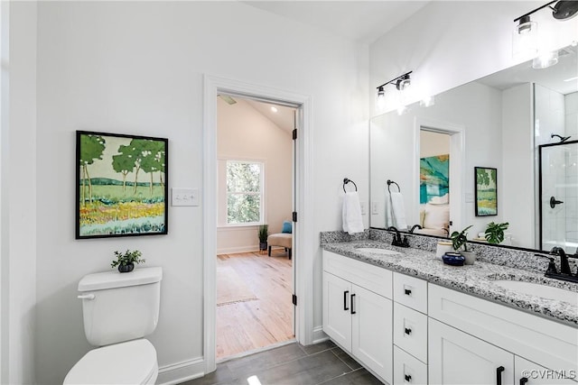 bathroom with toilet, a shower with door, double vanity, and a sink