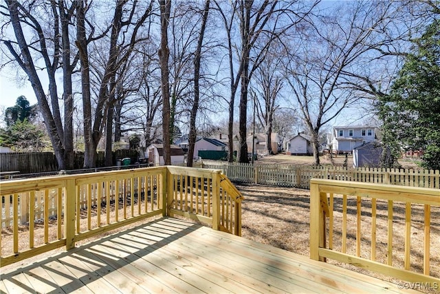 deck with a storage shed, a fenced backyard, a residential view, and an outdoor structure