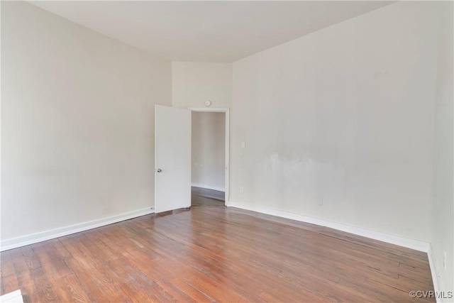 spare room with baseboards and wood finished floors