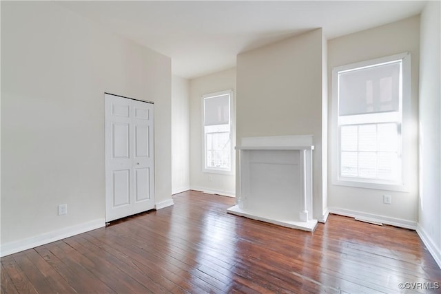 unfurnished living room featuring hardwood / wood-style flooring and baseboards