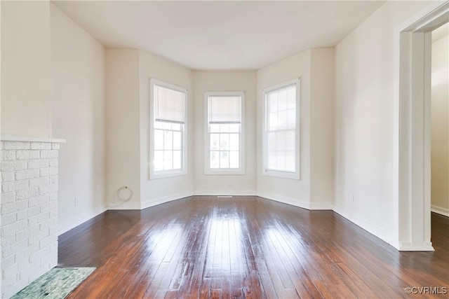 unfurnished living room featuring dark wood-style floors, a fireplace, and baseboards