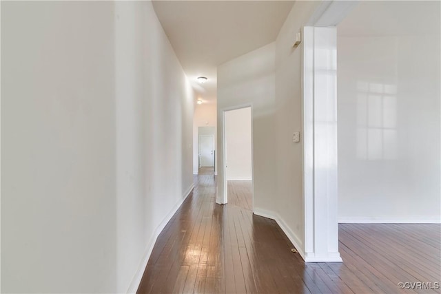 corridor with dark wood finished floors and baseboards