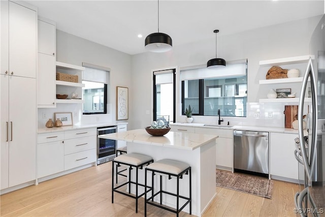 kitchen featuring stainless steel appliances, wine cooler, open shelves, and a sink