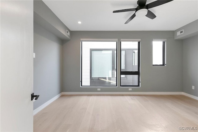 empty room featuring baseboards, ceiling fan, visible vents, and light wood-style floors