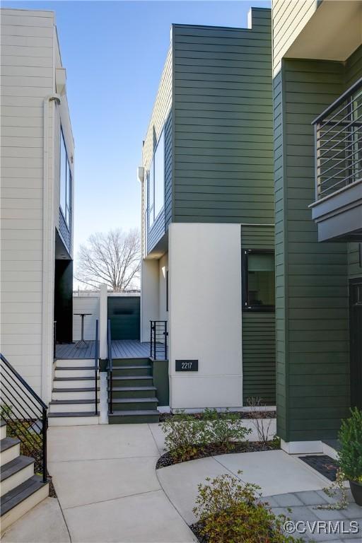 view of property exterior featuring stucco siding, stairs, and a wooden deck