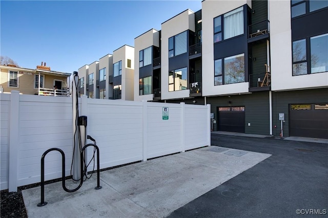 exterior space featuring a residential view, fence, and an attached garage