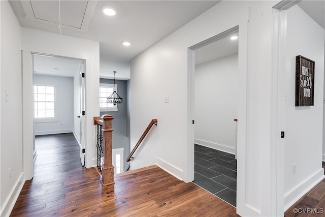 hall with dark wood-style flooring, recessed lighting, attic access, an upstairs landing, and baseboards