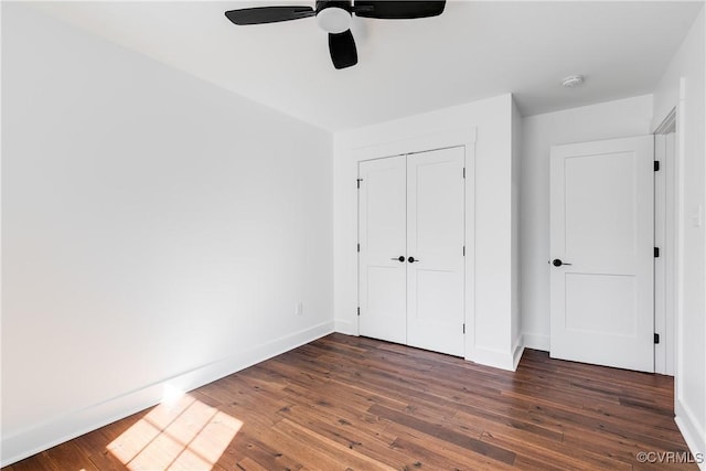 unfurnished bedroom featuring hardwood / wood-style flooring, a ceiling fan, baseboards, and a closet