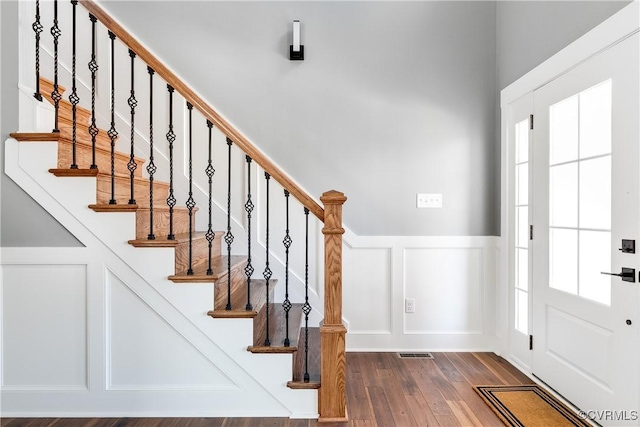 entrance foyer with a wainscoted wall, visible vents, a decorative wall, and wood finished floors