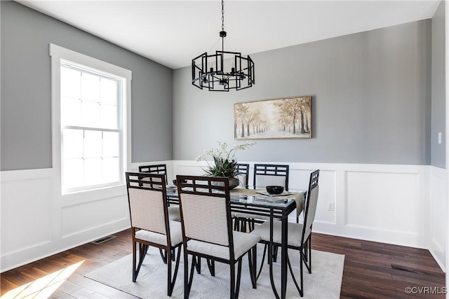 dining area with wainscoting, dark wood finished floors, visible vents, and a notable chandelier