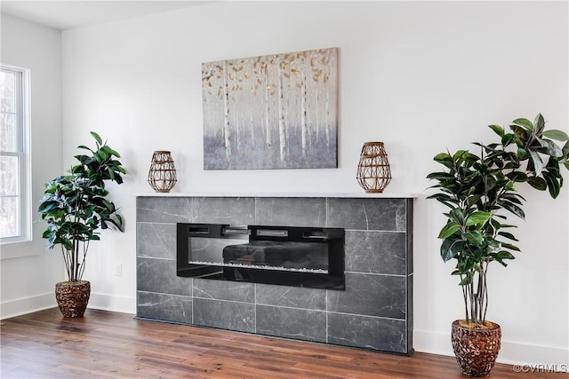 interior details featuring a fireplace, wood finished floors, and baseboards