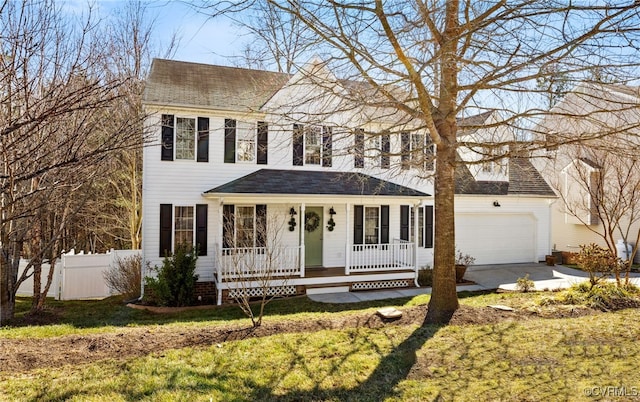 colonial inspired home with a porch, an attached garage, fence, driveway, and a front yard