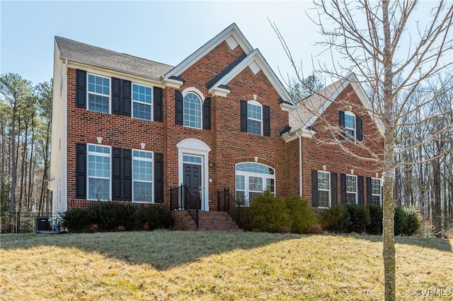 colonial home featuring brick siding, a front yard, and cooling unit