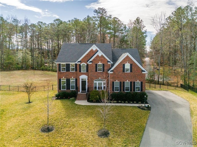 view of front of home featuring driveway, a front yard, fence, and brick siding