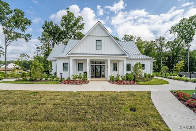 modern farmhouse featuring a porch, board and batten siding, a front yard, a standing seam roof, and metal roof