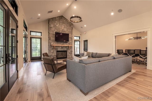 living room featuring visible vents, a stone fireplace, light wood-type flooring, high vaulted ceiling, and recessed lighting