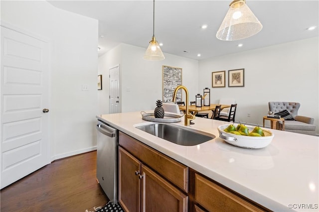 kitchen with hanging light fixtures, stainless steel dishwasher, light countertops, and a sink