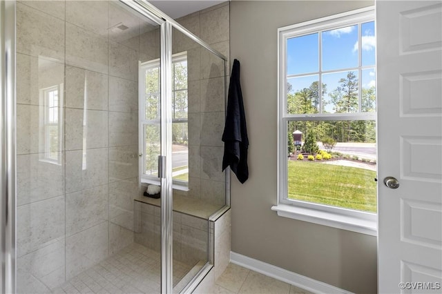 full bath with tile patterned flooring, plenty of natural light, a shower stall, and baseboards