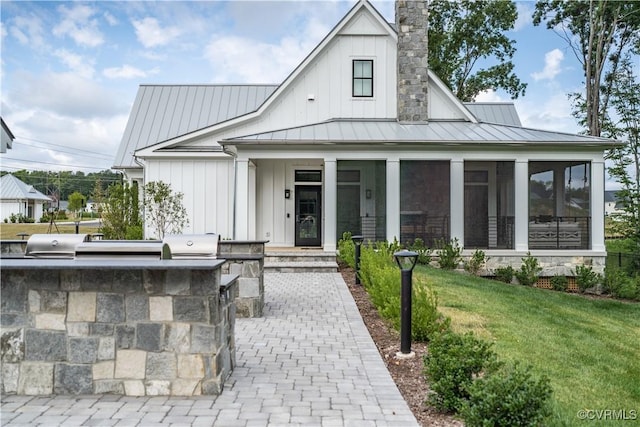 modern farmhouse featuring board and batten siding, a standing seam roof, a chimney, and area for grilling