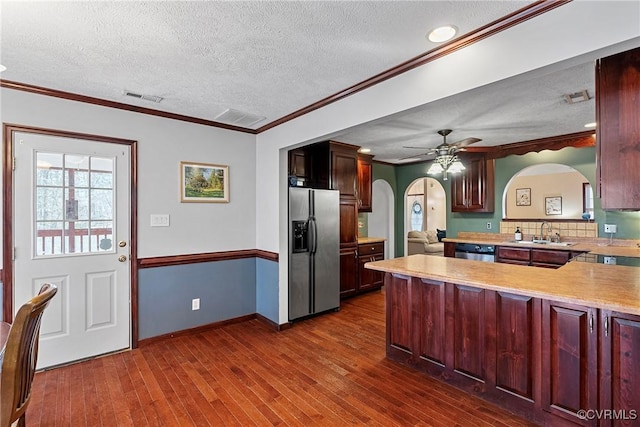 kitchen with arched walkways, stainless steel appliances, light countertops, visible vents, and a sink